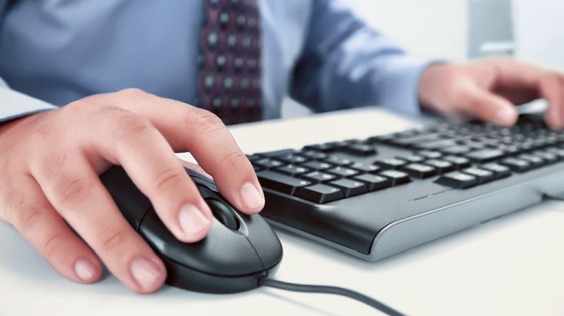 A businessman types on a computer, using the NiCE drag and drop feature to organize his work.