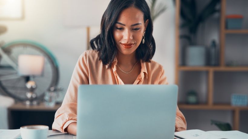 A woman works on a laptop, checking online with NiCE platform visible on the screen.